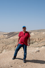 An enterprising man stands on top of a mountain and enjoys a beautiful view during a bright sunny day.