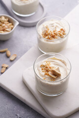 Creamy dairy yoghurt dessert with mascarpone, cream cheese and peanut butter in glasses on marble tray