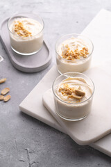Creamy dairy yoghurt dessert with mascarpone, cream cheese and peanut butter in glasses on marble tray