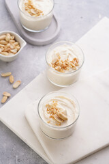 Creamy dairy yoghurt dessert with mascarpone, cream cheese and peanut butter in glasses on marble tray