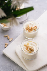 Obraz na płótnie Canvas Creamy dairy yoghurt dessert with mascarpone, cream cheese and peanut butter in glasses on marble tray