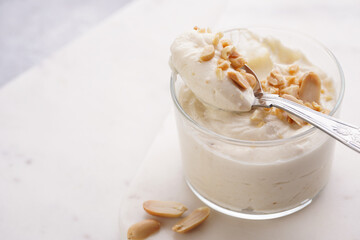 Creamy dairy yoghurt dessert with mascarpone, cream cheese and peanut butter in glasses on marble tray