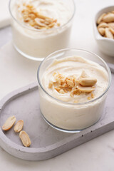 Creamy dairy yoghurt dessert with mascarpone, cream cheese and peanut butter in glasses on concrete tray