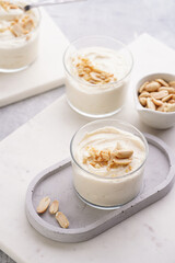 Creamy dairy yoghurt dessert with mascarpone, cream cheese and peanut butter in glasses on concrete tray
