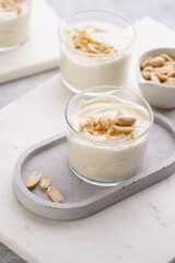Creamy dairy yoghurt dessert with mascarpone, cream cheese and peanut butter in glasses on concrete tray