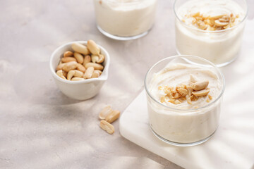 Creamy dairy yoghurt dessert with mascarpone, cream cheese and peanut butter in glasses on marble...