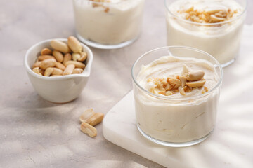 Creamy dairy yoghurt dessert with mascarpone, cream cheese and peanut butter in glasses on marble tray