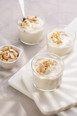Creamy dairy yoghurt dessert with mascarpone, cream cheese and peanut butter in glasses on marble tray