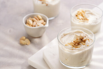Creamy dairy yoghurt dessert with mascarpone, cream cheese and peanut butter in glasses on marble tray