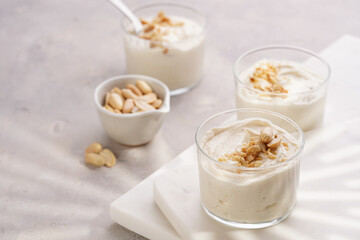 Creamy dairy yoghurt dessert with mascarpone, cream cheese and peanut butter in glasses on marble tray
