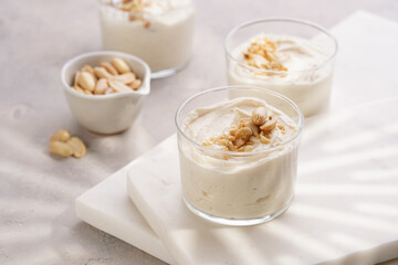 Creamy dairy yoghurt dessert with mascarpone, cream cheese and peanut butter in glasses on marble tray