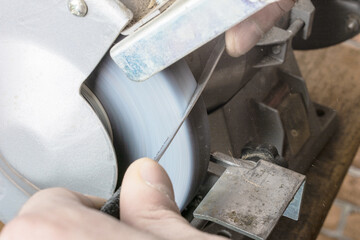 Knife sharpener and hand with blade on table, closeup