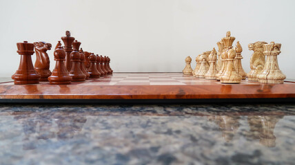 Pieces on a wooden chessboard. Side view. Pawns face to face.