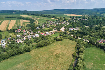 Aerial landscape view of green cultivated agricultural fields with growing crops and distant village houses