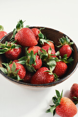 Fresh strawberries in a clay bowl on white background
