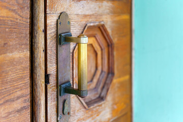Old copper handle with scuffs on the wooden door