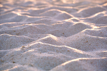Close up of clean yellow sand surface covering seaside beach illuminated with evening light. Travel and vacations concept