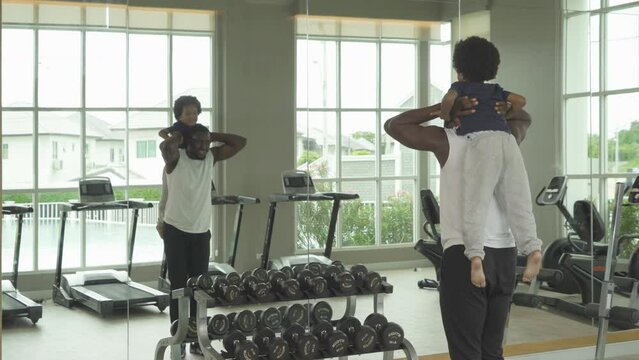Relaxed black african american family, dad and son playing, doing exercise, working out, and training in gym or fitness center in sport and recreation concept. People lifestyle activity.