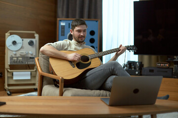 Male musician play acoustic guitar conduct online lesson on laptop. Man singer composer perform...