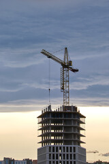 Dark silhouette of tower cranes at high residential apartment buildings construction site at sunset. Real estate development © bilanol