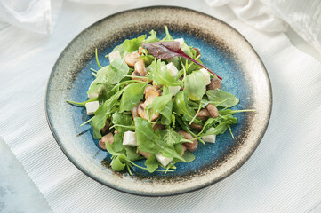 Spinach salad with mushrooms and feta cheese on a blue plate
