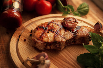 A piece of pork on a wooden board with a jar of garlic and basil ketchup