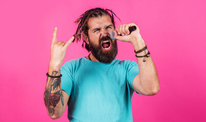 Bearded man singing in microphone with horns gesture heavy metal rock. Hipster enjoying karaoke.
