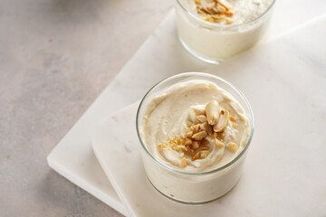 Creamy dairy yoghurt dessert with mascarpone, cream cheese and peanut butter in glasses on marble tray with a tea spoon