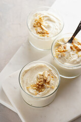 Creamy dairy yoghurt dessert with mascarpone, cream cheese and peanut butter in glasses on marble tray with a tea spoon