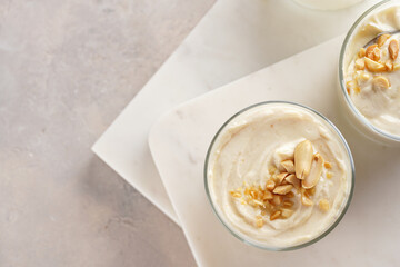 Creamy dairy yoghurt dessert with mascarpone, cream cheese and peanut butter in glasses on marble tray with a tea spoon