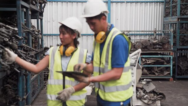 Foreman is checking second-hand parts in the warehouse. Manager and administrator standing in the large warehouse. Worker at a automotive spare parts warehouse.