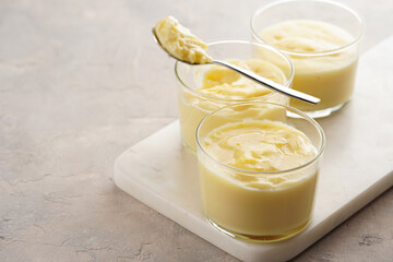 Creamy french vanilla pudding in glass on marble board on grey neutral background
