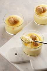 Creamy french vanilla pudding in glass decorated with italian biscuits amaretti on marble board on grey neutral background