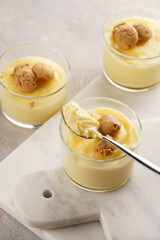 Creamy french vanilla pudding in glass decorated with italian biscuits amaretti on marble board on grey neutral background