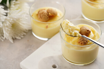 Creamy french vanilla pudding in glass decorated with italian biscuits amaretti on marble board on grey neutral background