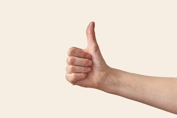 Male hand with thumb up on cream background.