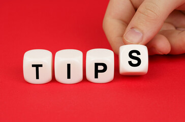On a red background, a person's hand moves the cubes with the inscription - Tips