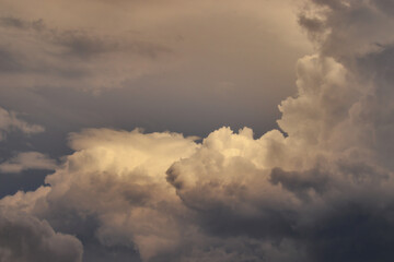 fluffy gray-shaded cumulus clouds framing piece of dark sky.