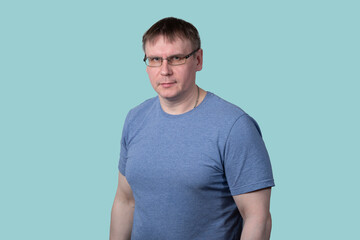 Fototapeta premium Portrait of a man with glasses and a blue T-shirt on a blue background.
