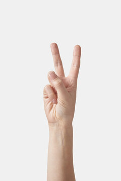 Victory gesturing female or V letter hand on white.