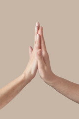 Two female high five gesturing hands on beige.