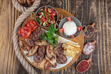 Turkish cuisine, mixed kebab. Meat platter fried on charcoal with spices on a wooden board. Rack of lamb, lamb, kebab, chicken, mushrooms and tomato sauces for meat.