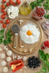 set of ingredients for making homemade pizza. Fresh cherry tomatoes and mushrooms, dough flour, mozzarella, olive oil and herbs, top view, copy space for your text