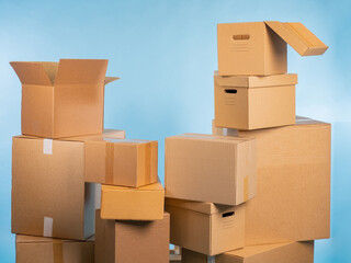 Cardboard boxes of different sizes. Lots of boxes for packing parcels. Concept of production of paper containers. Boxes on turquoise background. Mountain of cardboard parcels without inscriptions