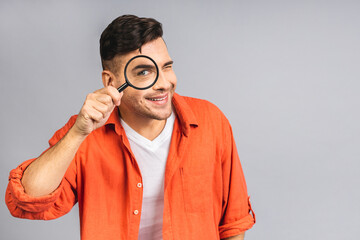 Ukrainian young student man isolated over grey white background with magnifying glass, has fun, happiness, cool emotion.