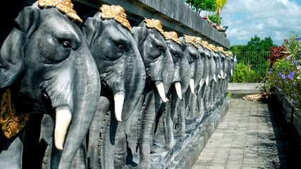 Statues of elephants in hats holding a concrete slab