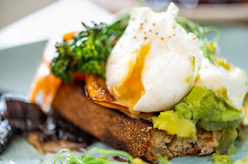 Healthy breakfast from poached eggs, steamed broccolli, salmon, smashed avocado, grilled mushrooms and tomato on toast