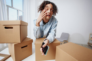 A young man unpacking things from boxes in the room interior