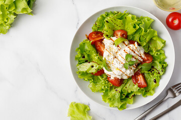 Salad with stracciatella cheese, green lettuce leaves, tomatoes, and sauce.  Keto diet, healthy and detox food concept. Vegetable salad bowl. Copy space
