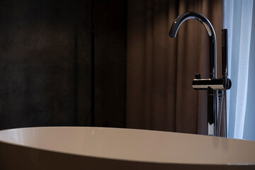 A new faucet in the bathroom in the interior of a hotel or a new dark apartment